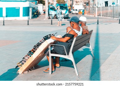 Salvador, Bahia, Brazil - October 01, 2021: Two street vendors sitting at Farol da Barra square in Salvador, Bahia, Brazil.