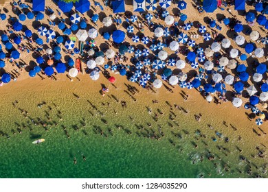 Salvador da Bahia, Brazil, aerial top view of umbrellas and people relaxing and bathing at Porto da Barra Beach on a sunny day.