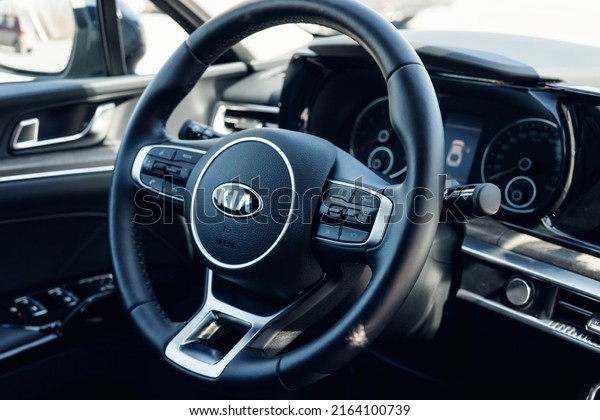 Samara, Russia - 04.16.2022: Close-up of the logo\
KIA K5 on the leather steering wheel. Multimedia leather steering\
wheel in a modern expensive car. Black car interior. Modern car\
interior detail