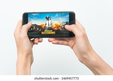 Samara, Russia -07, 29, 2019: A young guy plays a PUBG game on Iphone 8 Plus. Teenage boy holding a phone in his hands with a game PlayerUnknown's Battlegrounds on a white background.