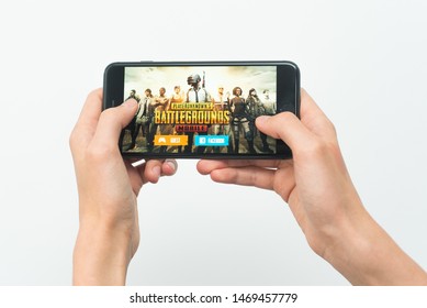Samara, Russia -07, 29, 2019: A young guy plays a PUBG game on Iphone 8 Plus. Teenage boy holding a phone in his hands with a game PlayerUnknown's Battlegrounds on a white background.
