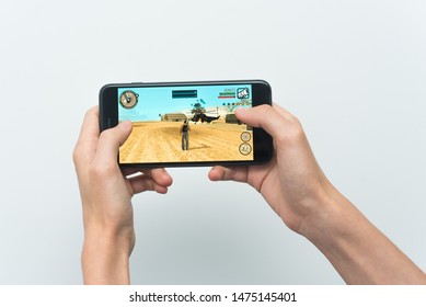 Samara, Russia -07, 29, 2019: A Young Guy Playing GTA Game On Iphone 8 Plus. Teenage Boy Holding A Phone In His Hands With A Game Grand Theft Auto: San Andreas On A White Background.