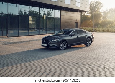 Samara, Russia - 08.18.2021: New Mazda 6 in Machine Gray color. Shooting a car at sunset, a contour light. A car on the background of a business center. The front part