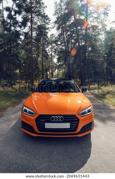 Samara, Russia - 09.05.2020: Orange AUDI A5 S\
line. A modern sports orange car is parked on a forest road. Travel\
concept. Pine forest at the\
sunset