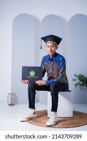Samarinda, 7 Jul, 21. The young man graduated over grey background studio. Asian man wearing blue batik