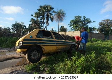 Sambouya, the Gambia, Africa, September 18, 2020, horizontal photography of a yellow and green taxi car, stuck in a big puddle of water, with people trying to get it out, outdoors on a sunny day