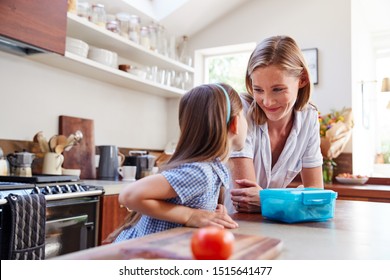 Same Sex Female Couple With Daughter Preparing School Lunchbox At Home Together