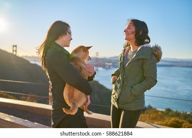 Same Sex Lesbian Couple With Pet Dog Shiba Inu On Hills In Front Of Golden Gate Bridge