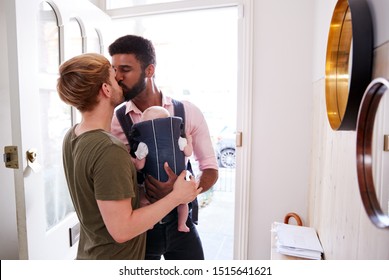 Same Sex Male Couple With Baby Daughter In Sling Opening Front Door Of Home