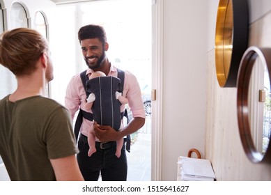 Same Sex Male Couple With Baby Daughter In Sling Opening Front Door Of Home