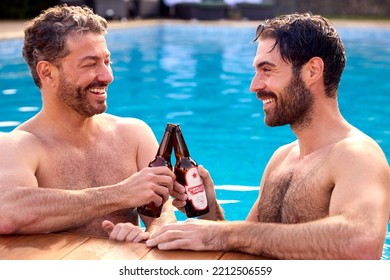 Same Sex Male Couple On Holiday In Swimming Pool Drinking Beer Together