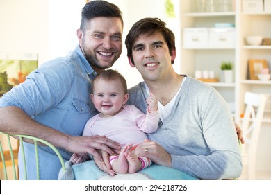 Same Sex Male Couple Smiling For The Camera With Their Daughters At Home. 