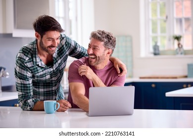 Same Sex Male Couple Using Laptop At Home To Check Finances Book Holiday Or Shop