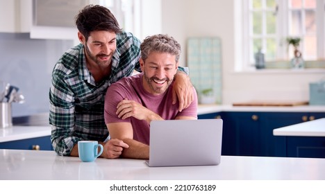 Same Sex Male Couple Using Laptop At Home To Check Finances Book Holiday Or Shop