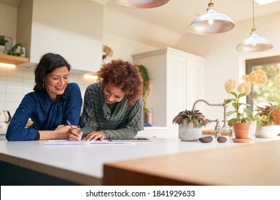 Same Sex Mature Female Couple Reviewing Domestic Finances And Investments In Kitchen At Home