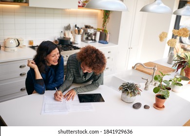 Same Sex Mature Female Couple Reviewing Domestic Finances And Investments In Kitchen At Home