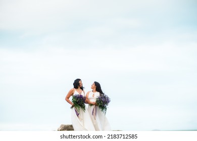 Same-sex Marriage Image Of Two Women On The Beach. Gay Girls Getting Married In A Beautiful Sunset On The Rocks Near The Beach. Real Wedding.