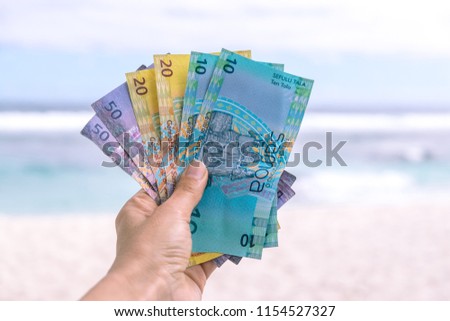 Samoan Tala currency (WST) - left hand holding colorful bank notes from Western Samoa in South Pacific