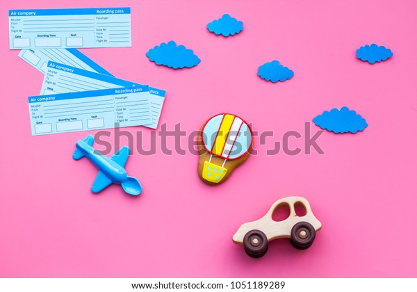 Sample of airplane ticket. Family trip with kid.\
Airplan, car and air balloon toys. Pink background flat lay space\
for text.