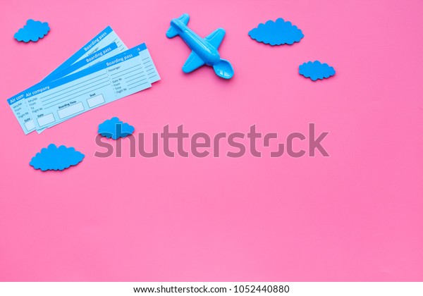 Sample of\
airplane ticket. Family trip with kid. Airplan toy and paper\
clouds. Pink background flat lay space for\
text