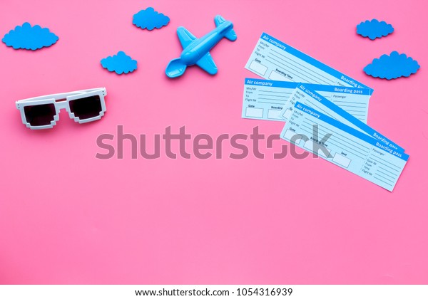 Sample\
of airplane ticket. Family trip with kid. Airplan toy and sun\
glasses. Pink background flat lay space for\
text