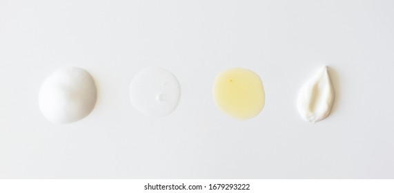 Sample Beauty Products For Facial Skin Care On White Background, Above. Cleanser Foam, Tonic, Oil Serum Essence Drop And Moisturizer Cream Smear