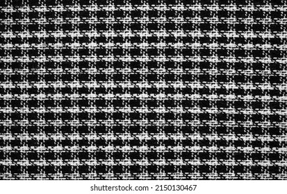 A sample of black and white fabric with a "houndstooth" pattern.  Image of tweed fabric with a small checkered pattern. Monochrome background with an abstract homogeneous texture.