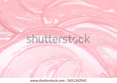 Sample of clear lip gloss on pink background, closeup