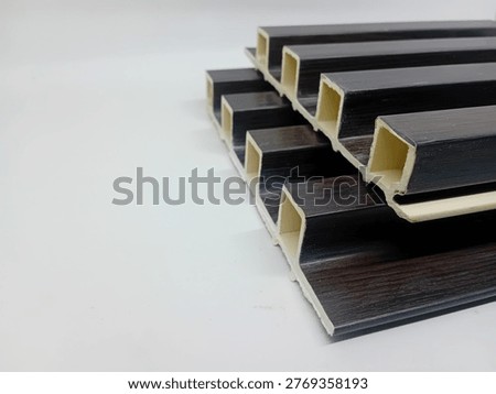 A sample cutout of a Wood Plastic Composite (WPC) wall panel with a white background, a modern wall decoration material. This panel is often referred to as a PVC wood lattice or fluted wall panel because it has a striped (embossed) texture that gives a 3D effect to the room.