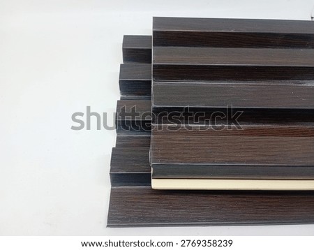 A sample cutout of a Wood Plastic Composite (WPC) wall panel with a white background, a modern wall decoration material. This panel is often referred to as a PVC wood lattice or fluted wall panel because it has a striped (embossed) texture that gives a 3D effect to the room.