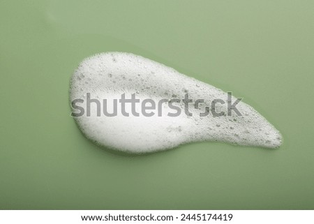 Sample of fluffy foam on green background, top view