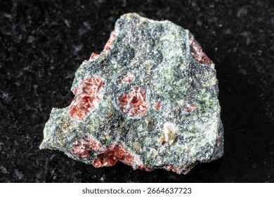 sample of pyrope garnets in rough rock on black granite background close up from Norway