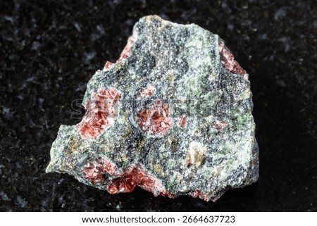 sample of pyrope garnets in rough rock on black granite background close up from Norway