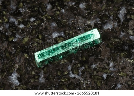 sample of rough emerald crystal on black granite background close up from Afghanistan