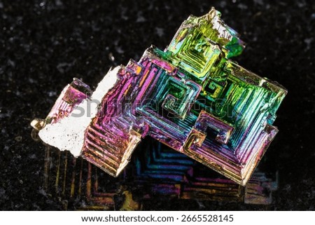 sample of rough grown bismuth crystals mineral on black granite background close up