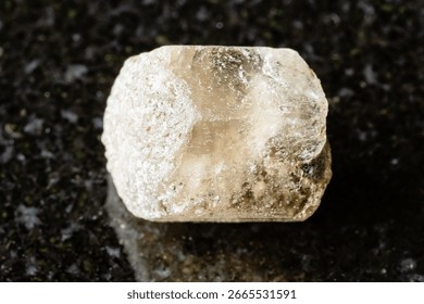 sample of rough phenakite stone on black granite background close up from Middle Urals, Russia