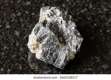 sample of rough wolframite rock on black granite background close up from Altai, Russia