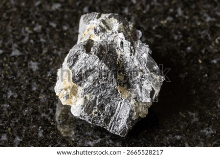sample of rough wolframite rock on black granite background close up from Altai, Russia