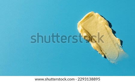 A sample of a yellow cosmetic product on a blue background. Swatch. Skin care. Sunscreen. Copy space