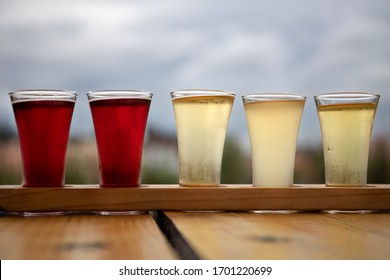 Sampler Flight Tray of Apple Cider Alcohol Drinks on a Wood Table Outdoors