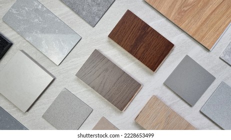samples of material including wooden engineering flooring tiles, grainy quartz stones, concrete tiles, wooden vinyl flooring tile, marble artificial stone. interior design selected material for idea. - Shutterstock ID 2228653499