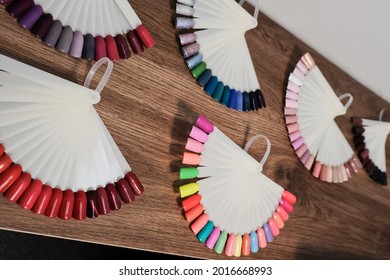 Samples Of Nail Polishes Of Different Colors Are Laid Out On The Manicure Table For Showing To Clients. Nail Acrylic Lacquer Manicure Swatches. Gel Nail Samples Palette.