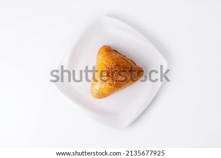 Samsa, triangular shaped samosa made of dough with filling in a white plate on a white background