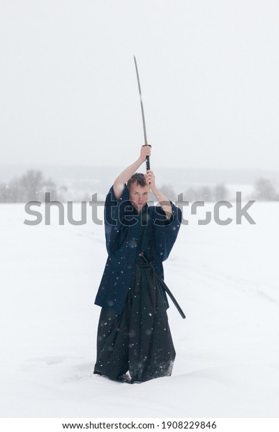 samurai warrior stands with sword and staff\
in the middle of an empty winter\
field