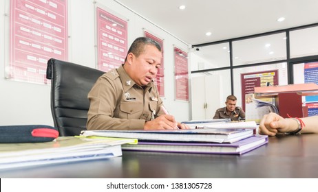 Samut Prakan, Thailand - April 26, 2019: Thai Police Officer (Police Sergeant Major) on duty at a local Thai police station accepting case and crime report