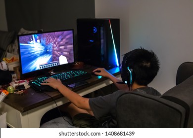 Samut Prakan, Thailand - May, 2019: Asian boy playing Minecraft on his computer with RGB gaming gear and peripherals