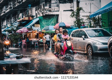Samutprakan,Thailand - October 18, 2017 : Families drive motorbikes among rain and floods in the alley.