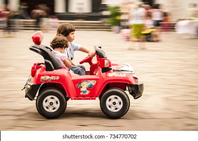 San Agustin, Colombia - December 15 2012: Boy and girl speeding over a market place in a toy car in Colombia.