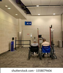 San Antonio, Texas, USA - November 7 2019: Unaccompanied Senior Adults Waiting At Departure Gate At The Airport Sitting On Black And Blue Whelchairs. Southwest Logo. Gate A14 