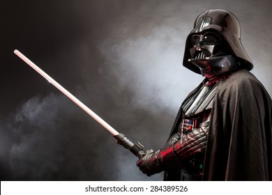 SAN BENEDETTO DEL TRONTO, ITALY. MAY 16, 2015. Portrait of Darth Vader costume replica with  his sword . Lord Fener is a fictional character of Star Wars saga.  Red grazing light and smoke